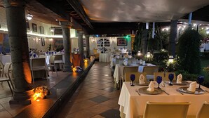 An outdoor dining area with tables set for service, featuring a tiled floor and columns. - Holiday Inn Cuernavaca by IHG (Cuernavaca)