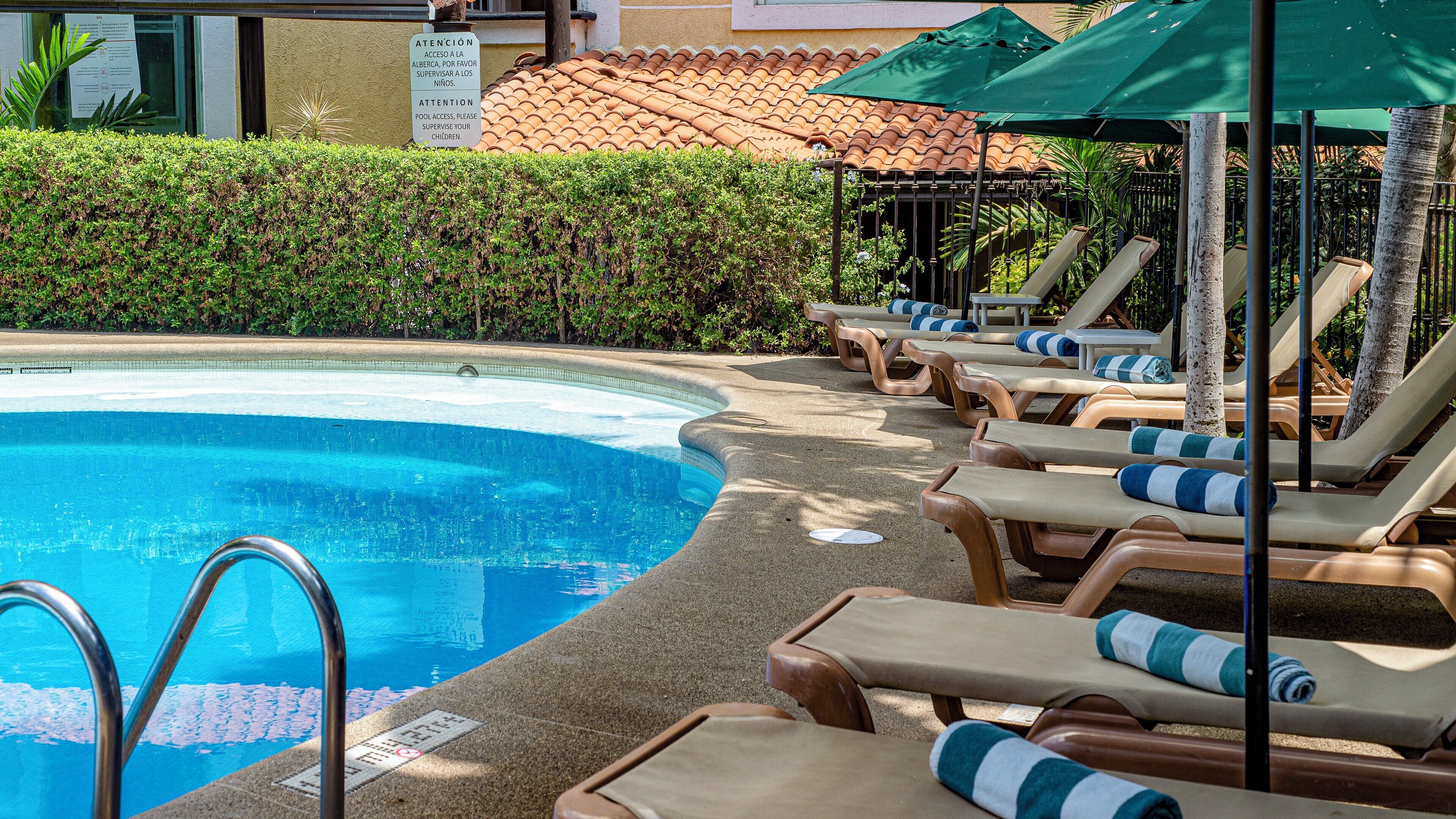 Un área de piscina con sillones de descanso y sombrillas.