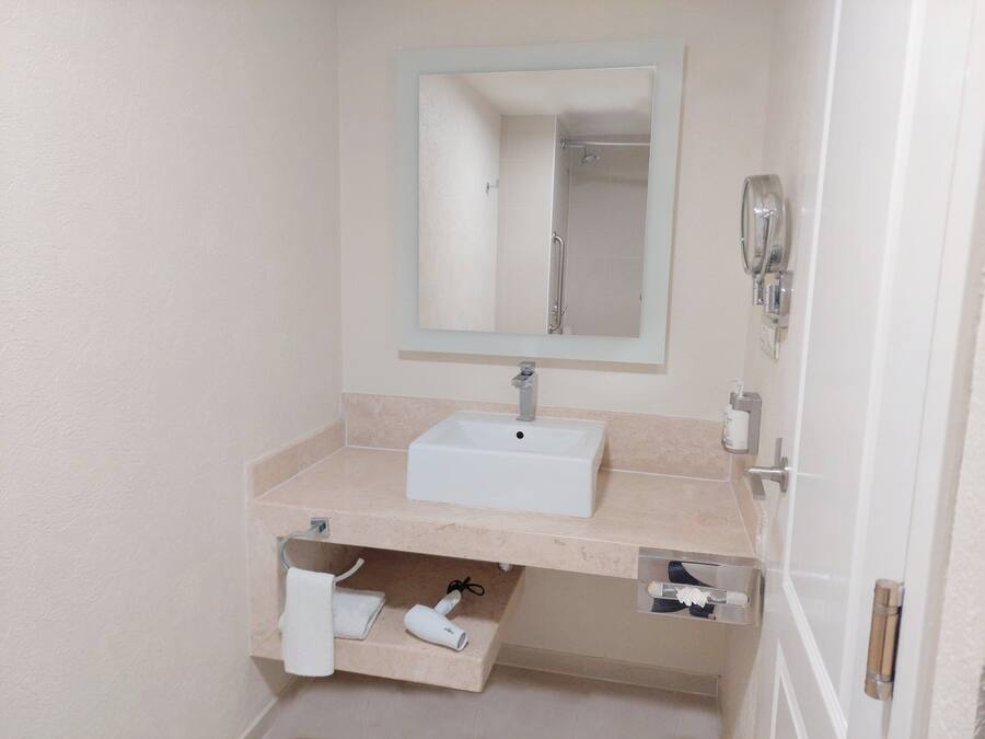 A bathroom with a white sink, a mirror, and a towel rack.