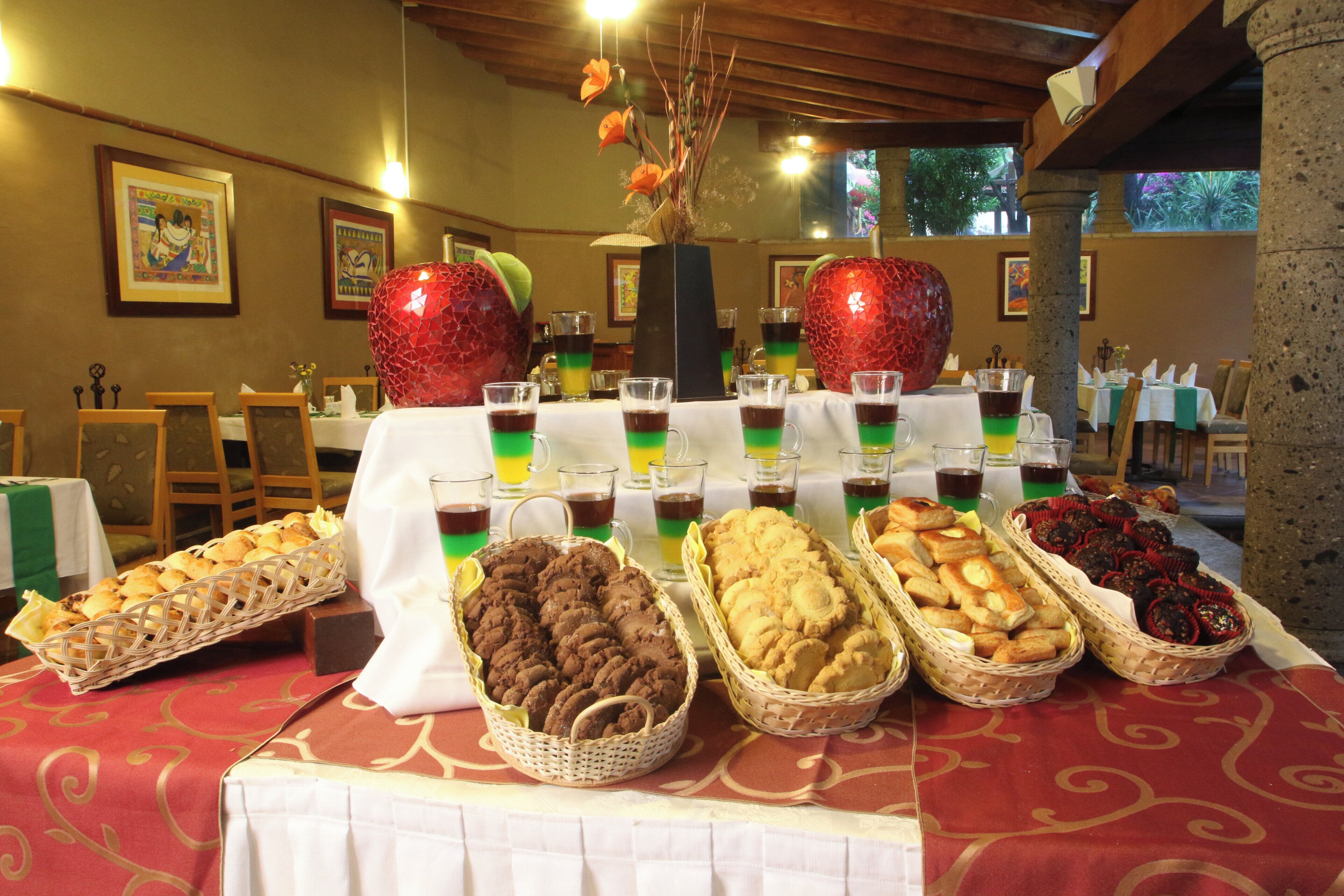 A buffet table with various food items and drinks, including cookies, pastries, and layered beverages.