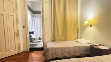 A hotel room with a bed, a nightstand, a lamp, a ceiling fan, and an air conditioning unit.