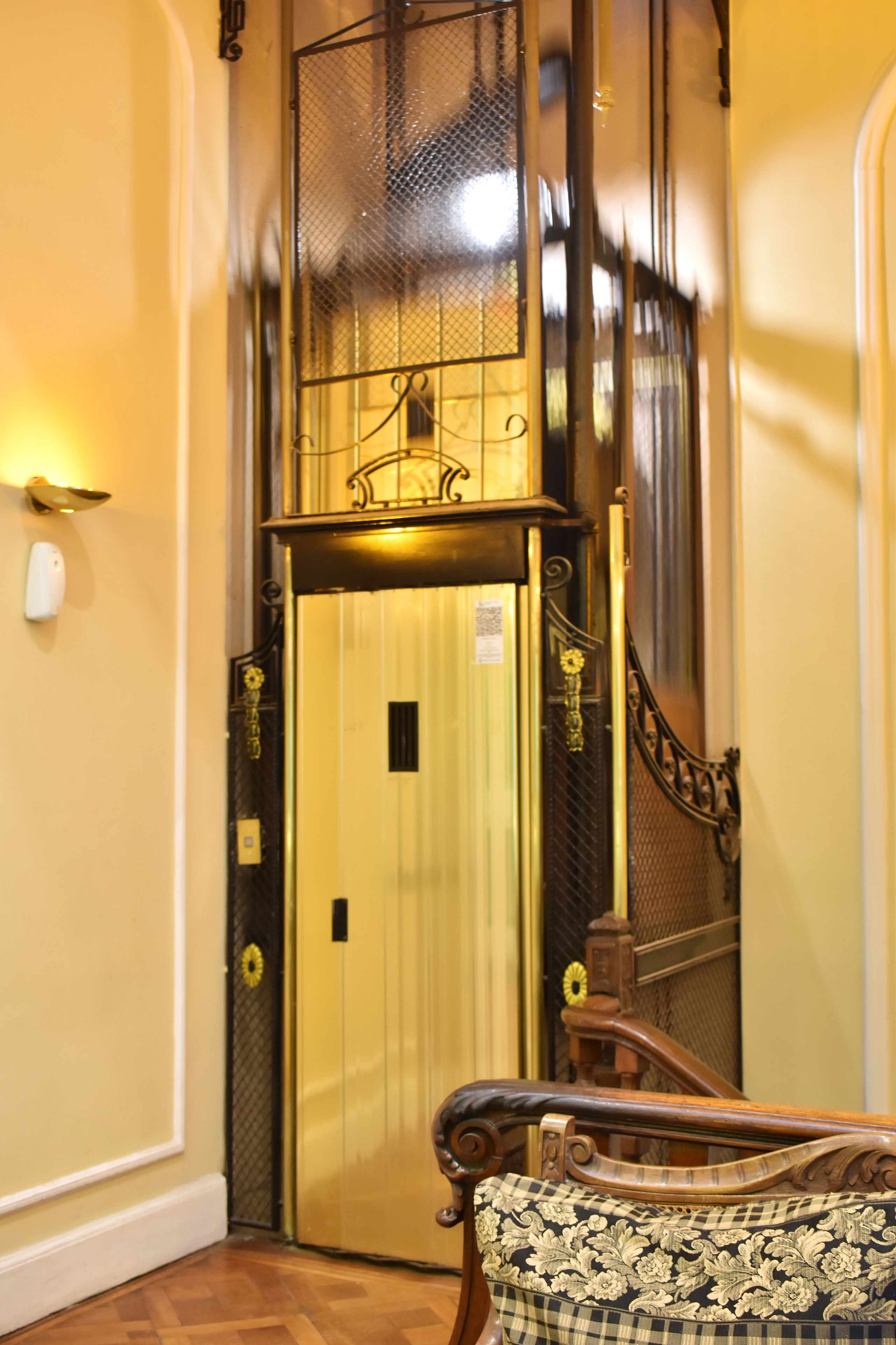An elevator with a decorative metal grille and a wall-mounted light fixture.