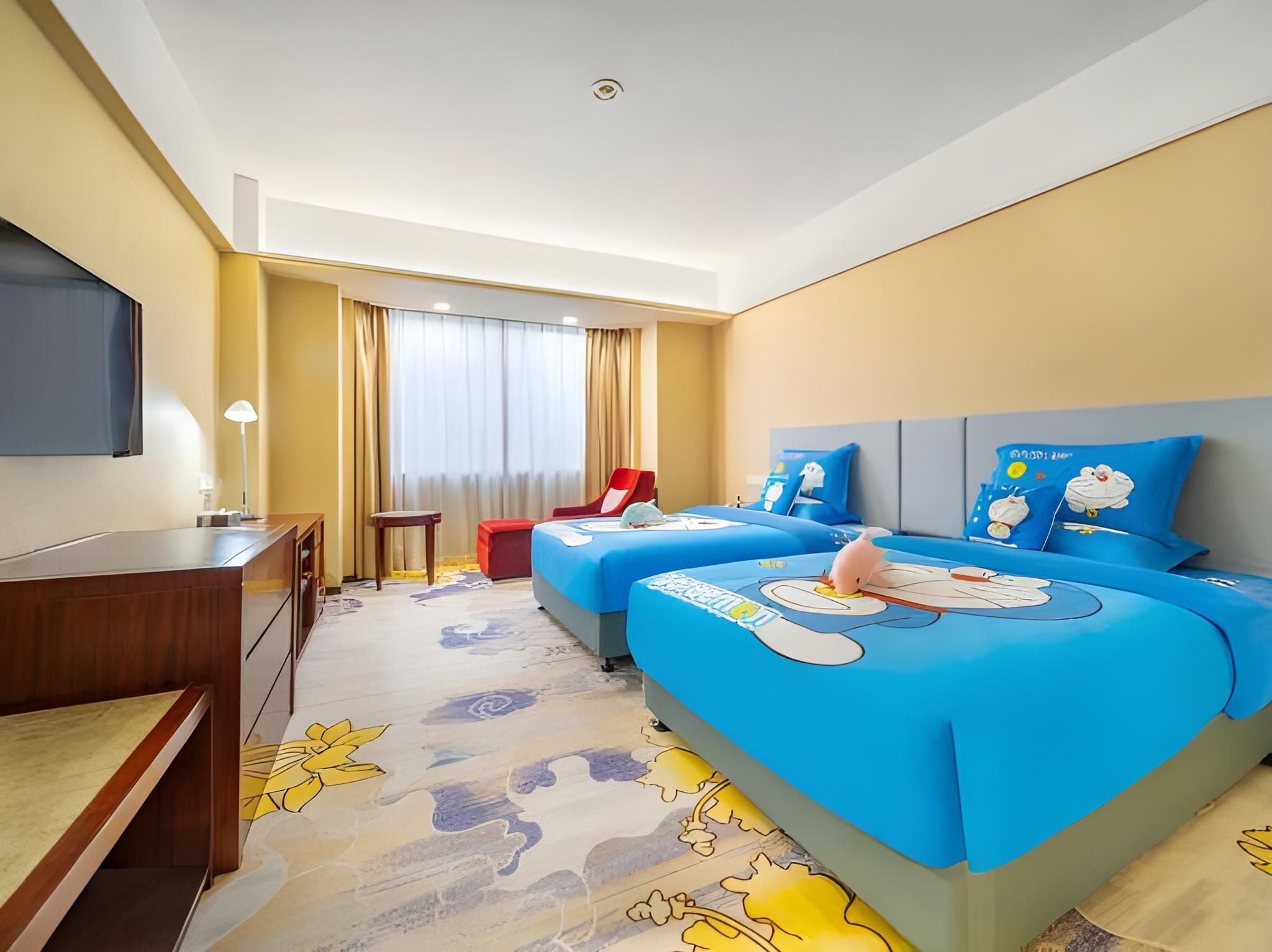 A hotel room with two beds, a desk, a chair, and a TV.