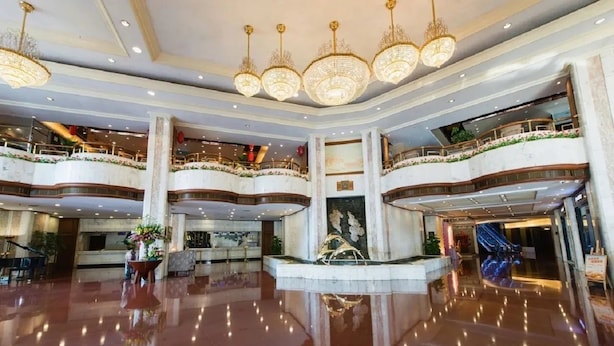 A spacious lobby with a polished floor, multiple levels with balconies, and ornate chandeliers. - Zhongshan International Hotel (Zhongshan)