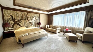 Amplia habitación de hotel con una cama grande, un sofá, una silla y una pequeña mesa.