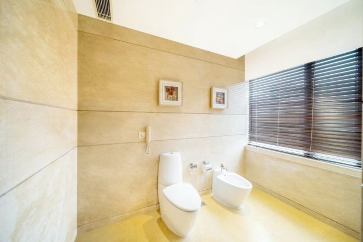 Un baño moderno con inodoro, bidé y ventana con persianas.