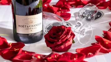 A bottle of Moët & Chandon champagne and two empty glasses on a table with red rose petals.