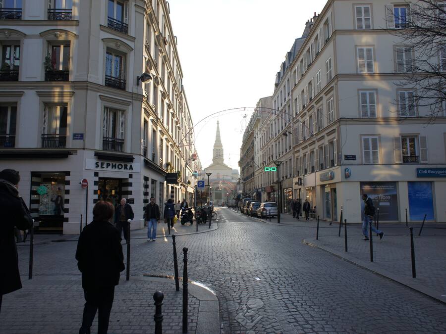 A cobblestone street lined with buildings, including a Sephora store.