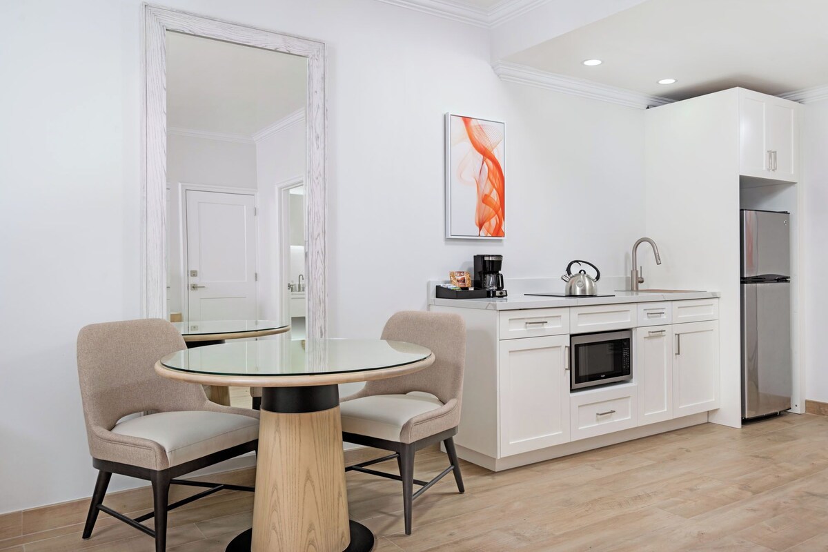 Una cocina moderna con armarios blancos, un refrigerador de acero inoxidable y una cafetera sobre la encimera.