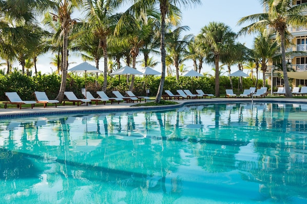 Una piscina al aire libre, sombrillas, sillones reclinables de piscina