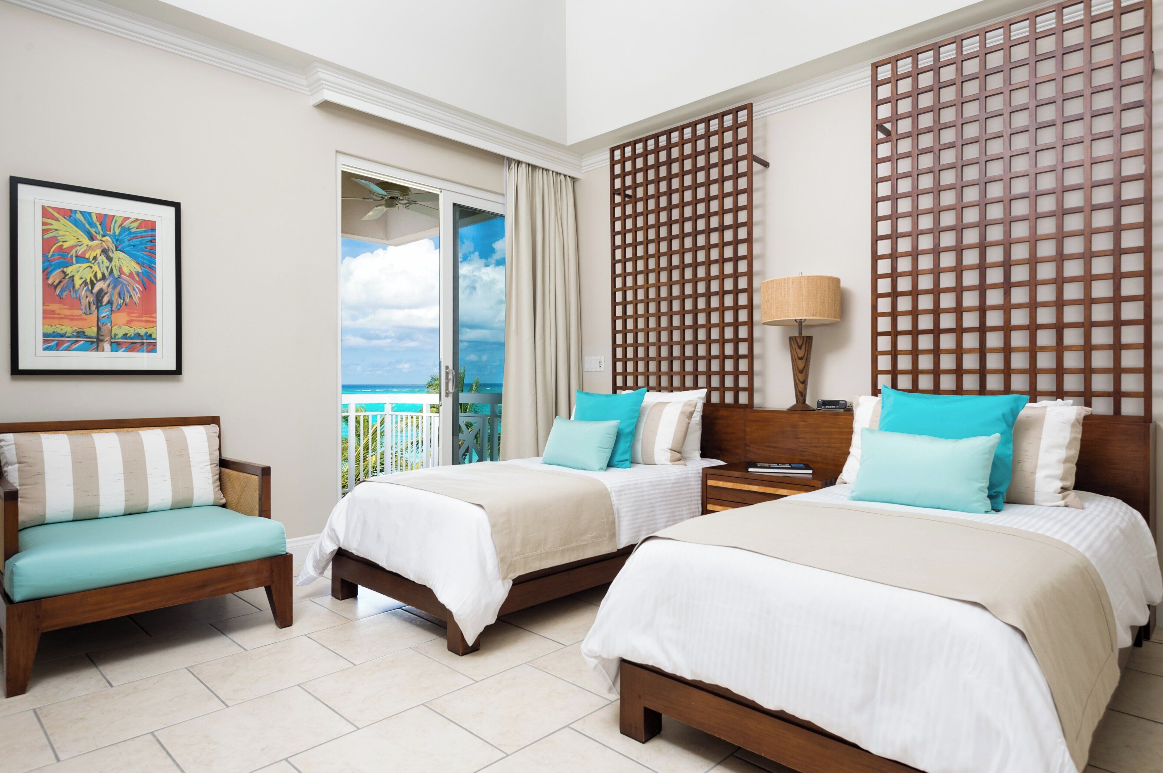 A hotel room with two beds, a sofa, a balcony with a view, and a decorative screen.
