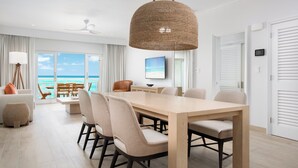 A modern dining area with a wooden table, beige chairs, and a woven pendant light. - Alexandra Resort - All-Inclusive (Providenciales)