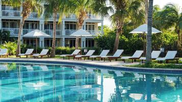 Alberca al aire libre, sombrillas en la alberca y camastros