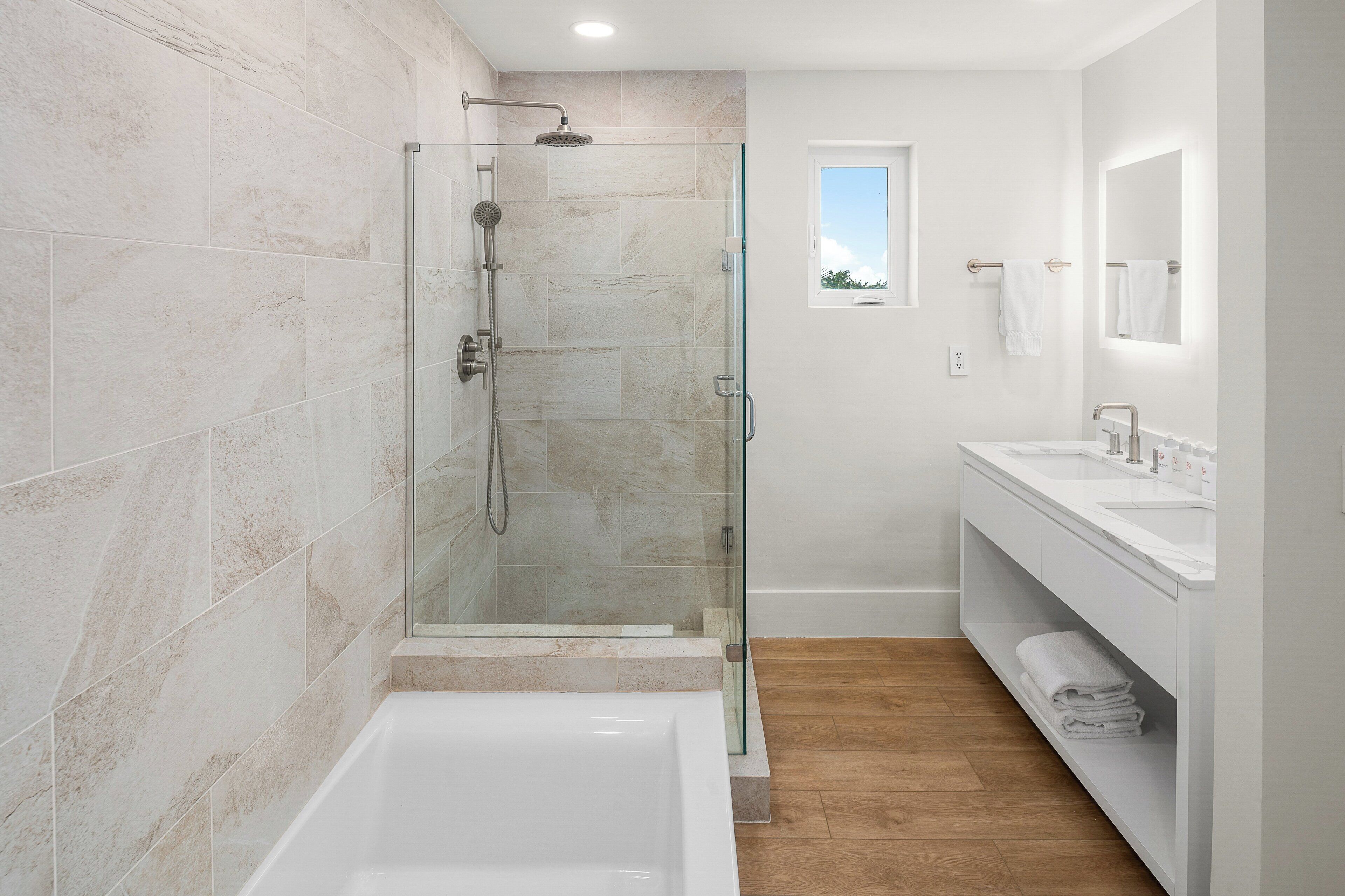 A modern bathroom with a glass-enclosed shower, a standalone bathtub, and a vanity with a mirror.