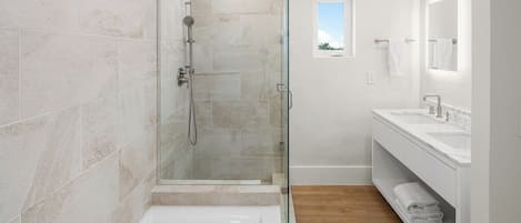 A modern bathroom with a glass-enclosed shower, a standalone bathtub, and a vanity with a mirror.