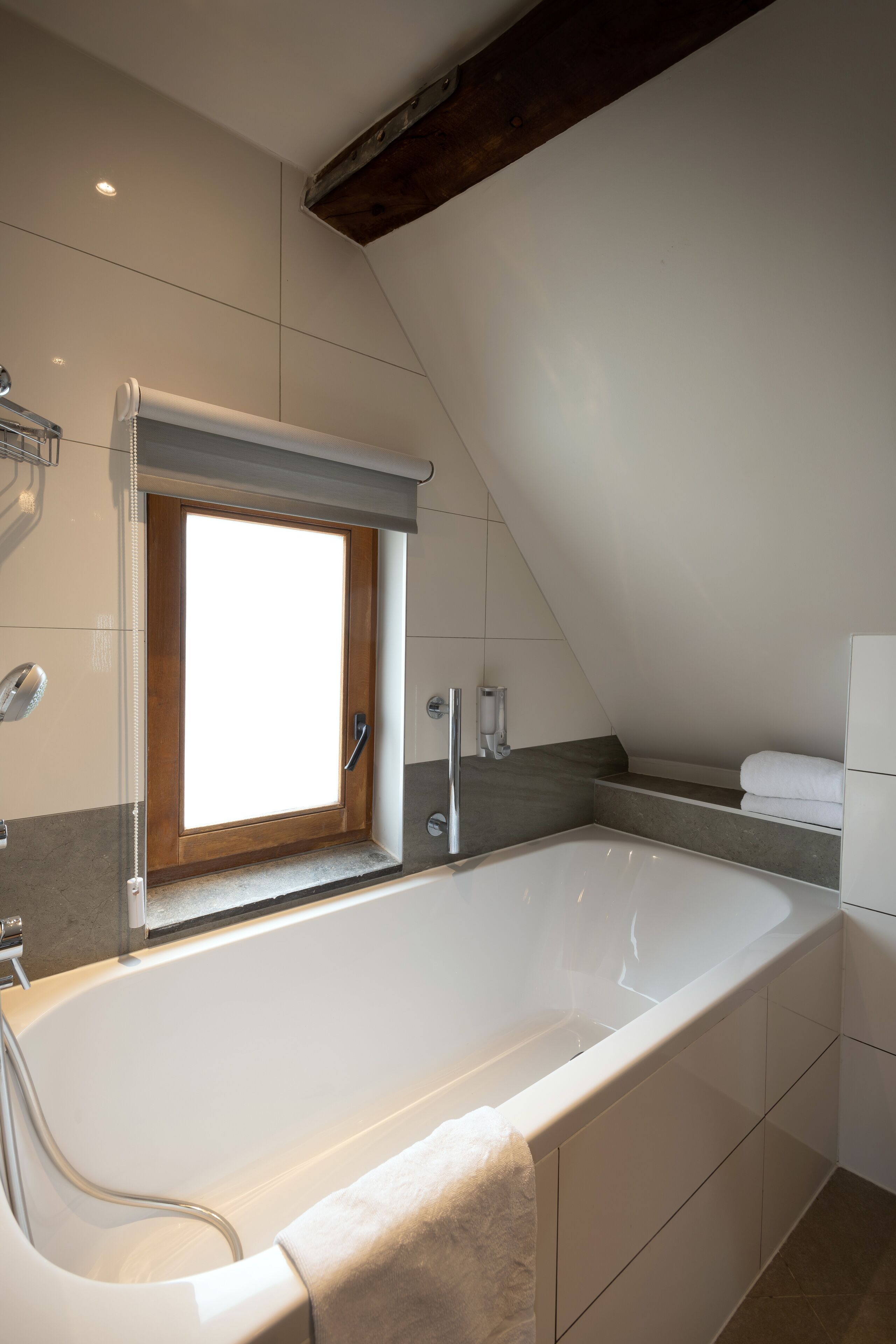 A modern bathroom with a freestanding bathtub, a window, and a towel rack.