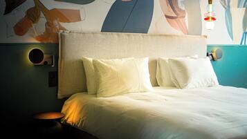 A neatly made bed with white linens, a textured headboard, and two wall-mounted light fixtures.