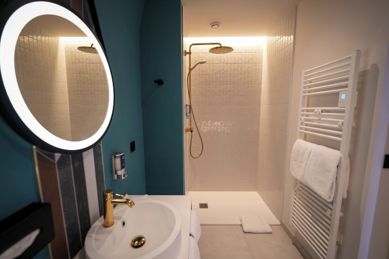 Une salle de bain équipée d’un lavabo, d’un miroir, d’une douche et d’un porte-serviettes.