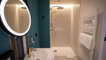 Une salle de bain équipée d’un lavabo, d’un miroir, d’une douche et d’un porte-serviettes.