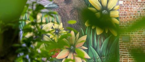 Un mural con un pájaro y flores sobre un muro de ladrillo.