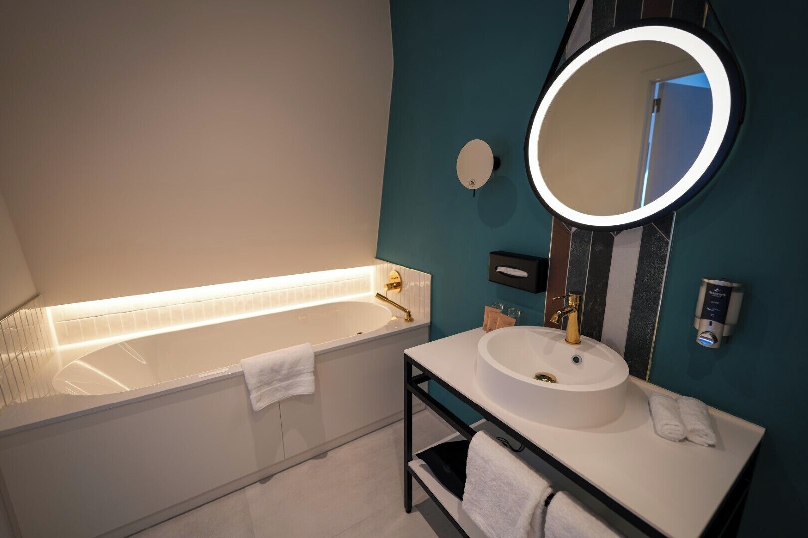 Une salle de bain moderne équipée d’une baignoire, d’un lavabo, d’un miroir et d’un porte-serviettes.