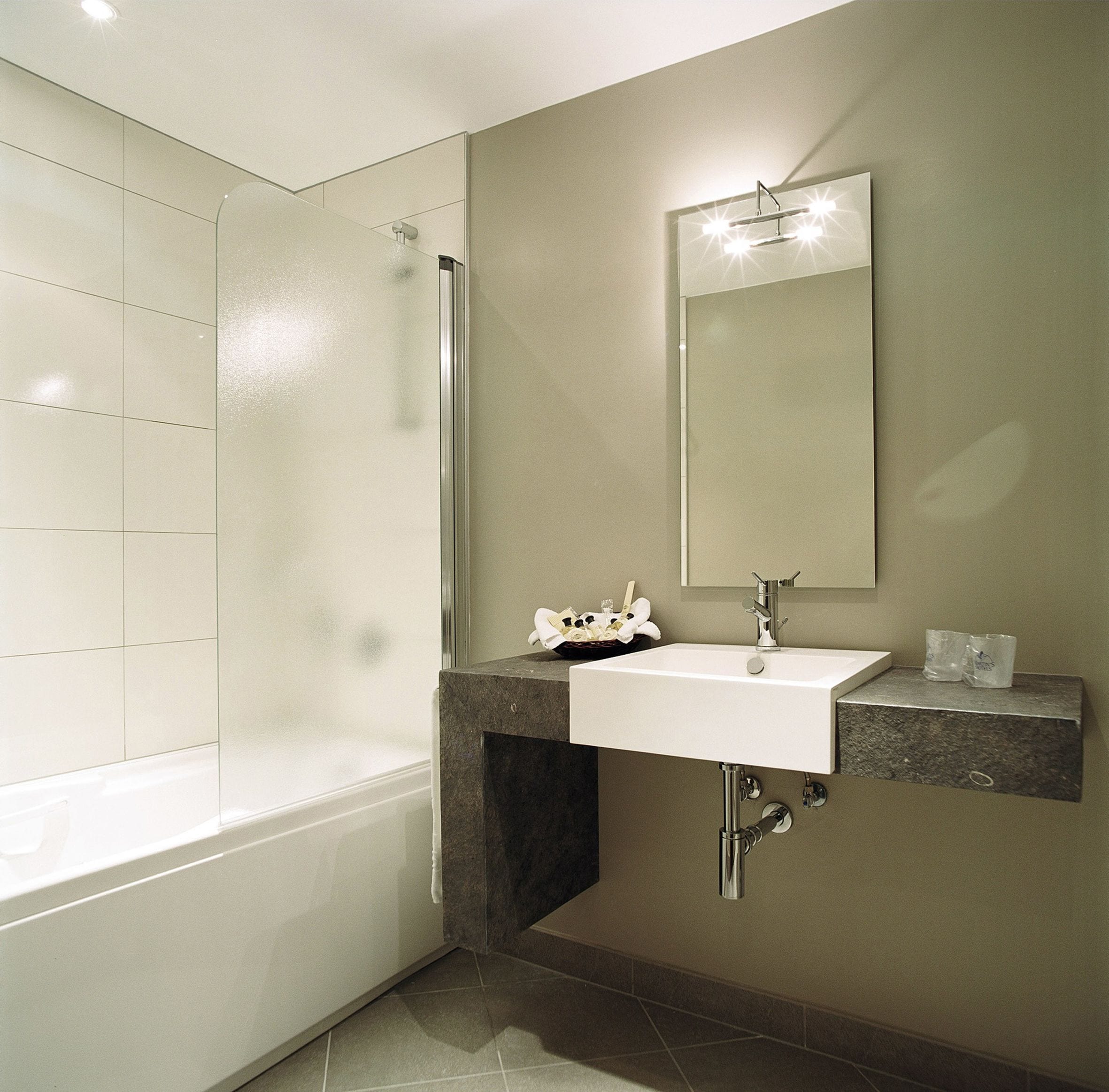 A modern bathroom with a bathtub, a shower, a sink, and a mirror.