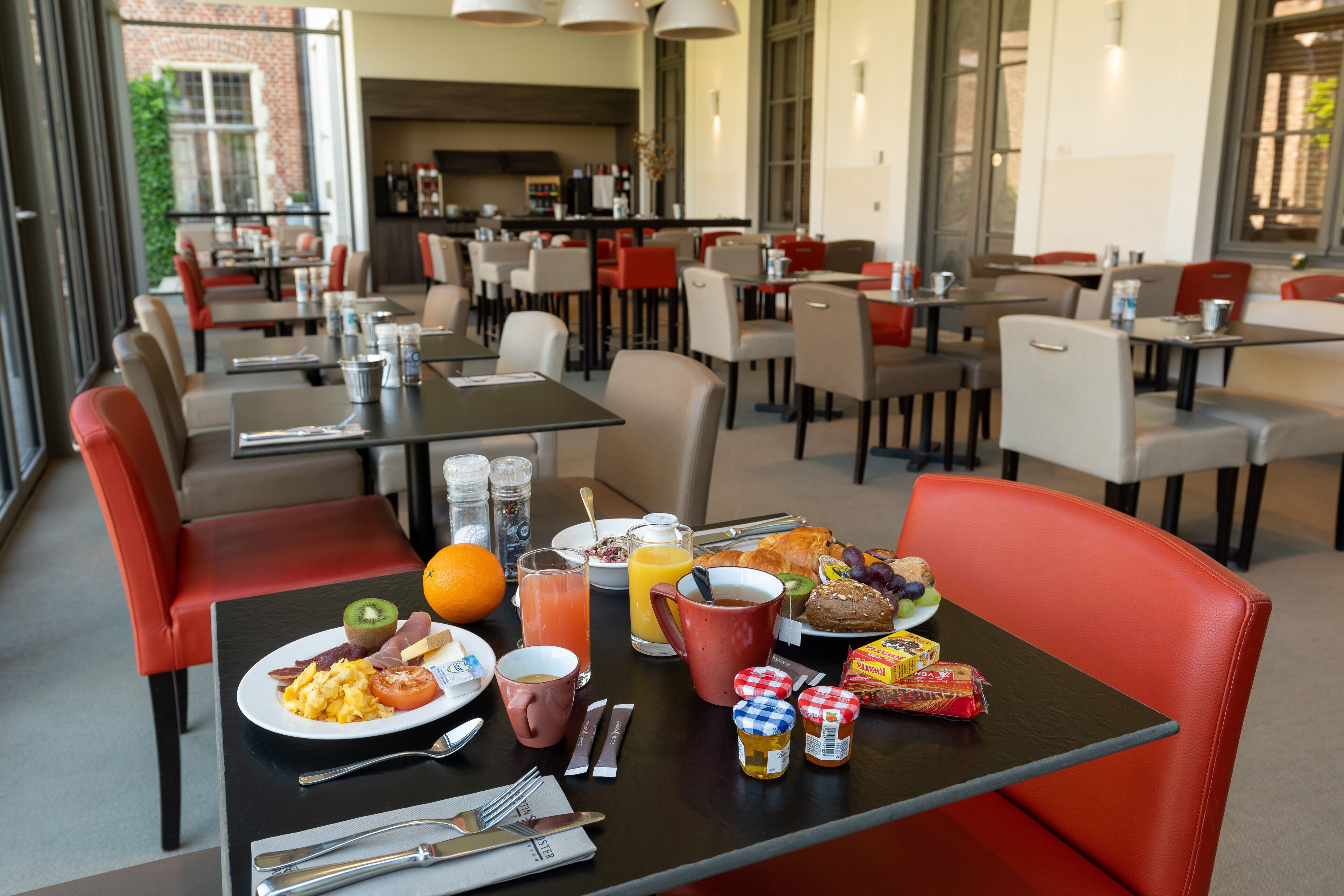 A dining area with tables and chairs, breakfast items, and a view of the outside.