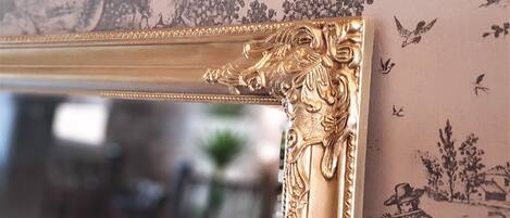 A gold-framed mirror with ornate carvings.