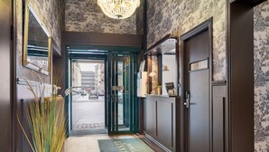 L’entrée d’un hôtel, avec une porte verte, un paillasson et un miroir accroché au mur.
