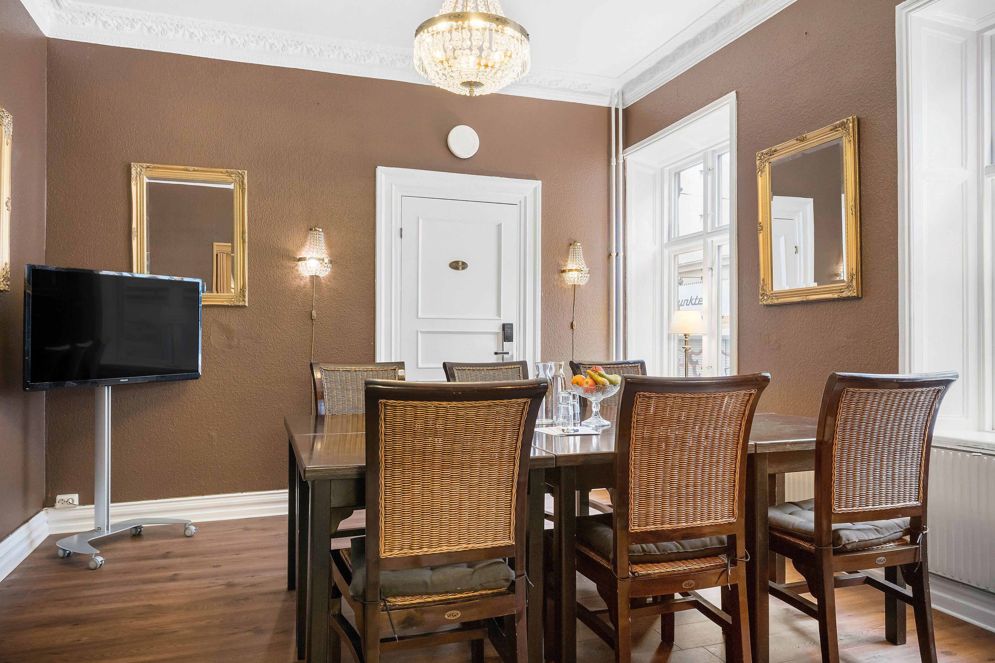 En matplats med en brun vägg, en vit dörr och en kristallkrona.
