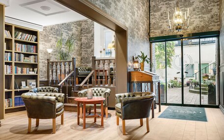 A library with leather armchairs, a wooden table, and a bookshelf filled with books.