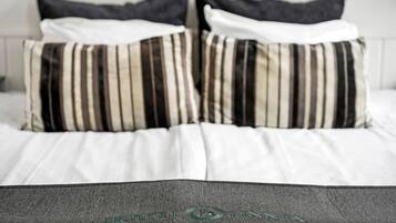 A bed with striped pillows and a gray throw blanket.