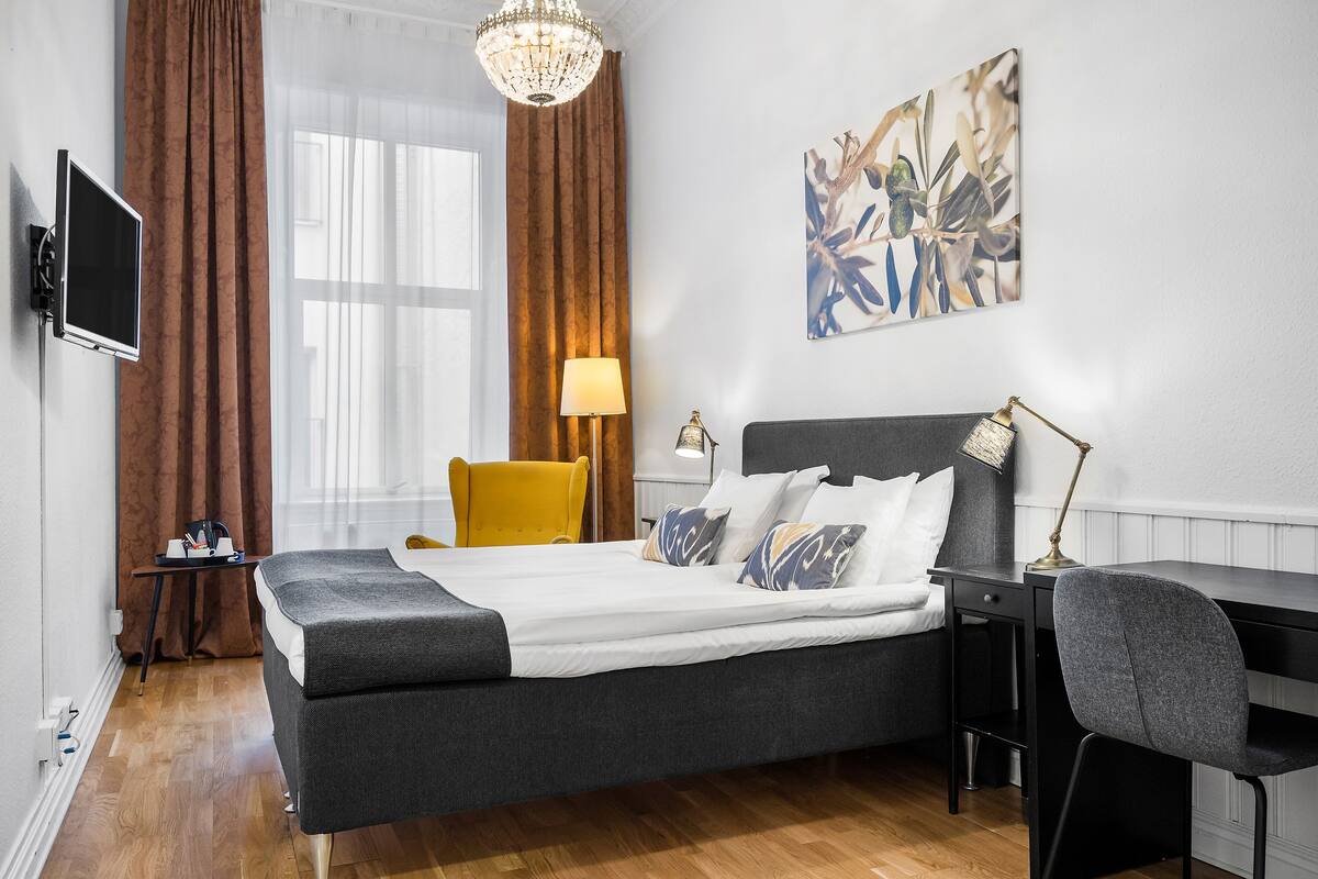 Quarto de hotel moderno com cama, escrivaninha e cadeira.