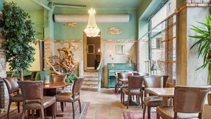 Un espace repas avec des chaises et des tables en bois, un lustre et un escalier menant à un niveau supérieur.