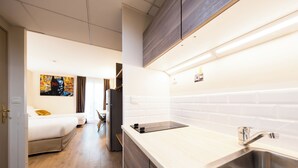 Una cocina moderna con un lavamanos de acero inoxidable, armarios de madera y un salpicadero de azulejos blancos.