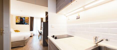 A modern kitchen with a stainless steel sink, wooden cabinets, and a white tiled backsplash.