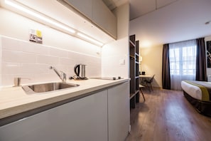 Una cocina moderna con un lavamanos, hervidor y una zona de comedor con mesa y sillas.