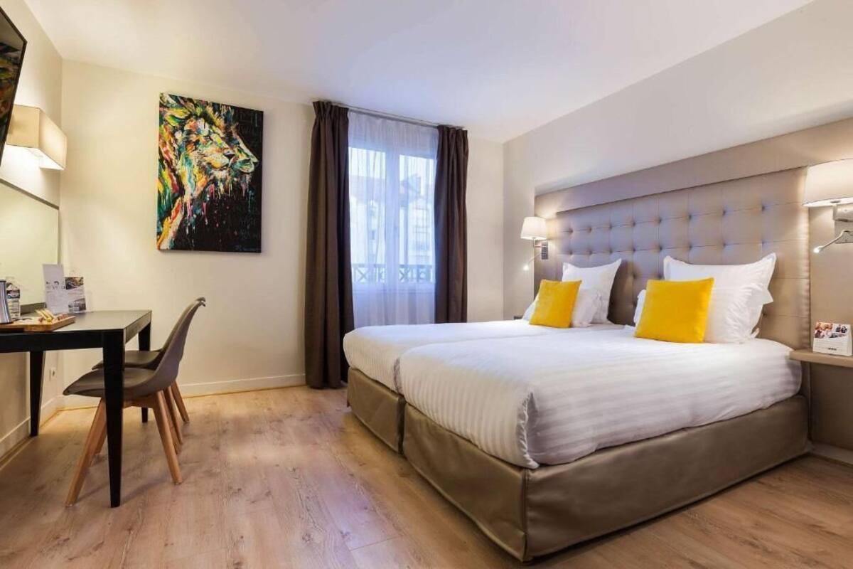 A hotel room with a large bed, a desk, and a chair.