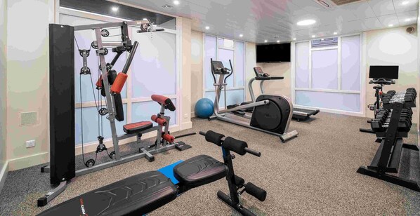 A gym with various exercise equipment including a bench press, a squat rack, and treadmills. - Best Western Hotel du Chateau Maisons Laffitte (Maisons-Laffitte)