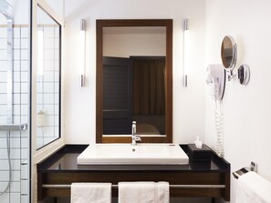 A bathroom with a white sink, a wooden vanity, a mirror, a hairdryer, and a towel rack. - Hotel Mercure Kourou Ariatel (Kourou)