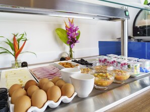 A buffet with eggs, fruits, and yogurt containers. - Hotel Mercure Kourou Ariatel (Kourou)