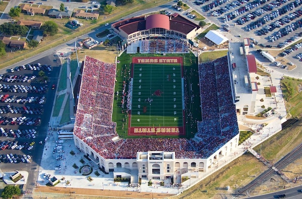 Vue aérienne d’un stade comprenant un terrain de football, des tribunes et des zones de stationnement.