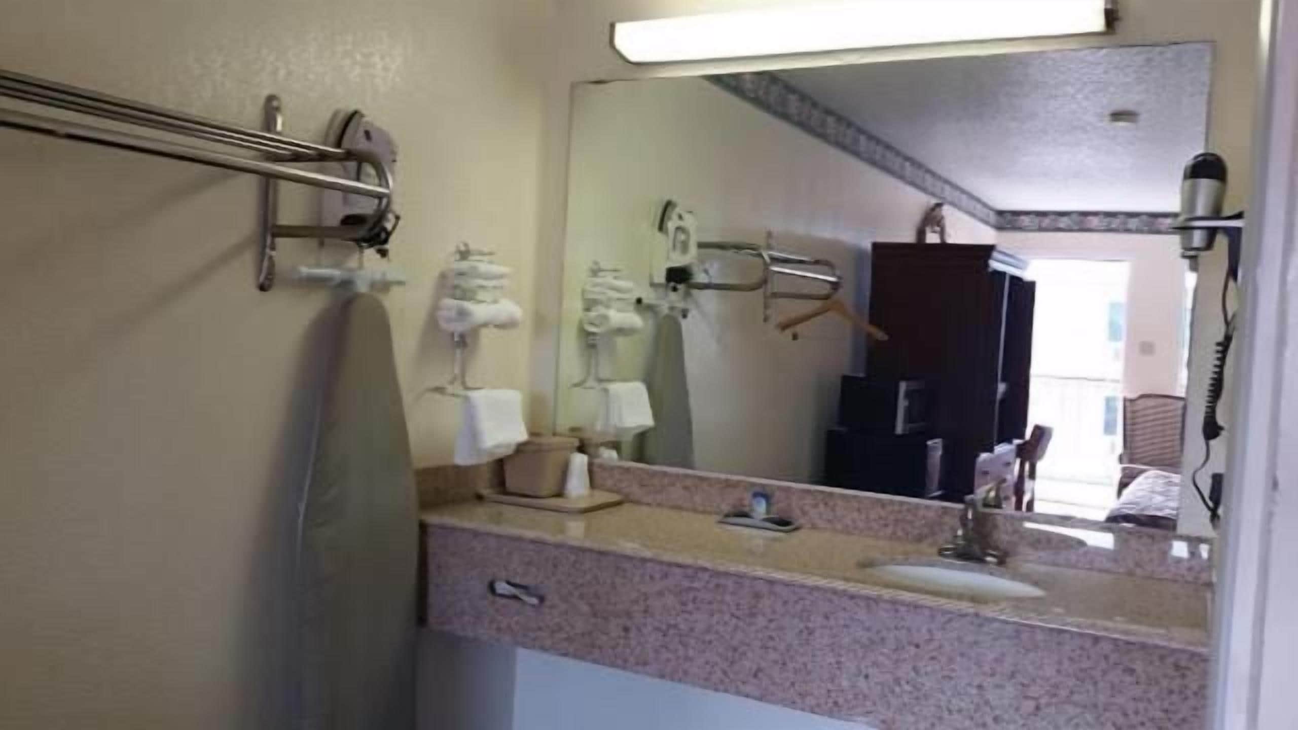 A bathroom with a mirror, a sink, and a towel rack.