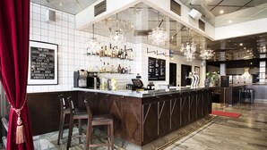 A bar area with a marble floor, a long counter with stools, and a menu board. - ProfilHotels Savoy (Jonkoping)
