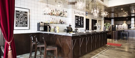 Zona de bar con suelo de mármol, una barra larga con taburetes y un panel con la carta.