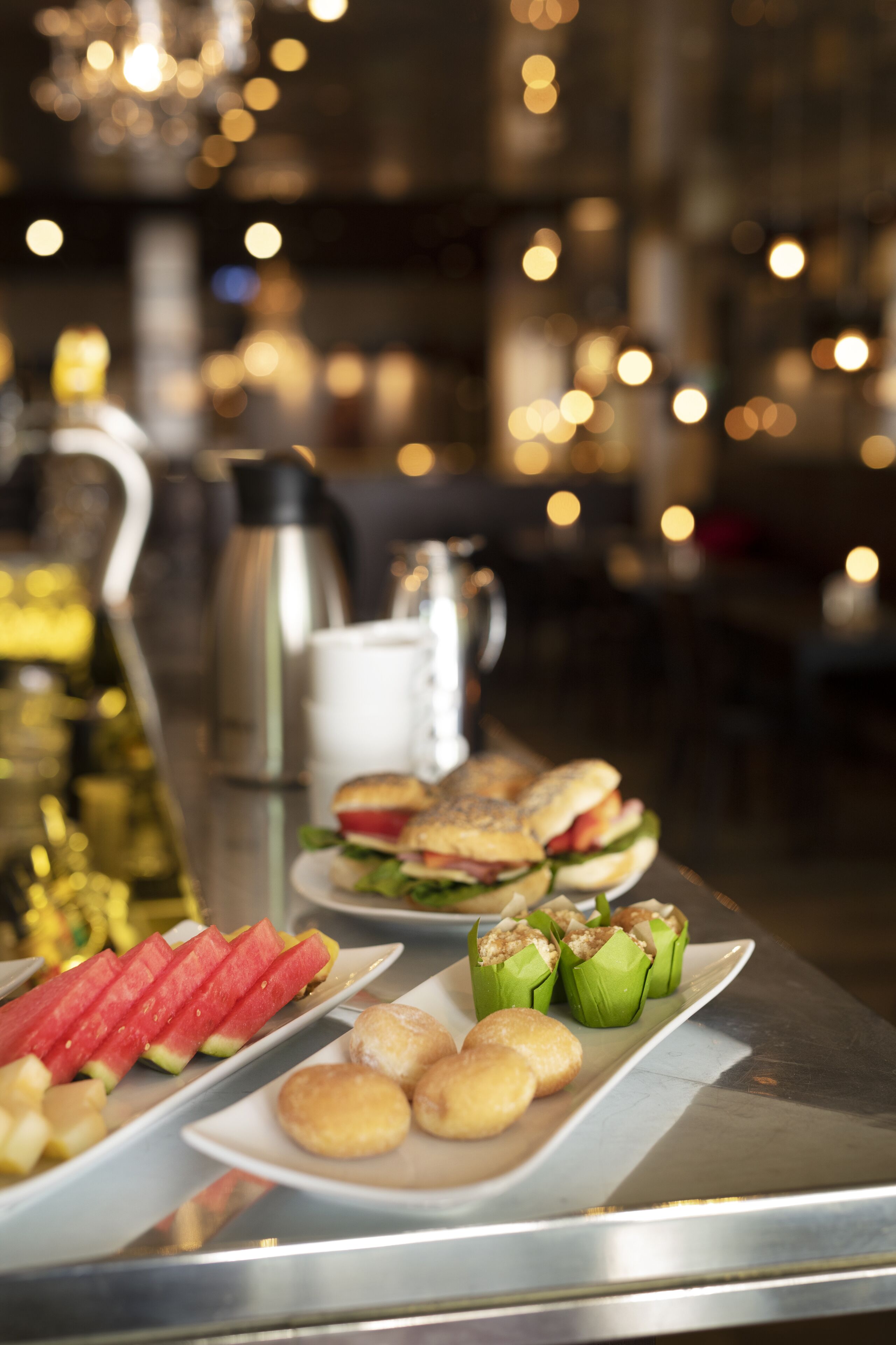 Una mesa de buffet con diferentes opciones de comida, incluyendo rebanadas de sandía, sándwiches y pasteles.