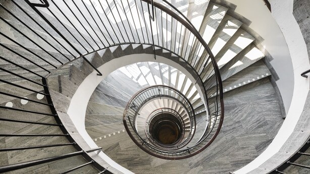 A spiral staircase with a central column and metal railings, surrounded by a curved wall. - ProfilHotels Savoy (Jonkoping)