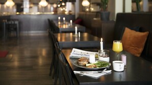 A dining area with a table set for a meal, including a sandwich, salad, and drinks. - ProfilHotels Savoy (Jonkoping)