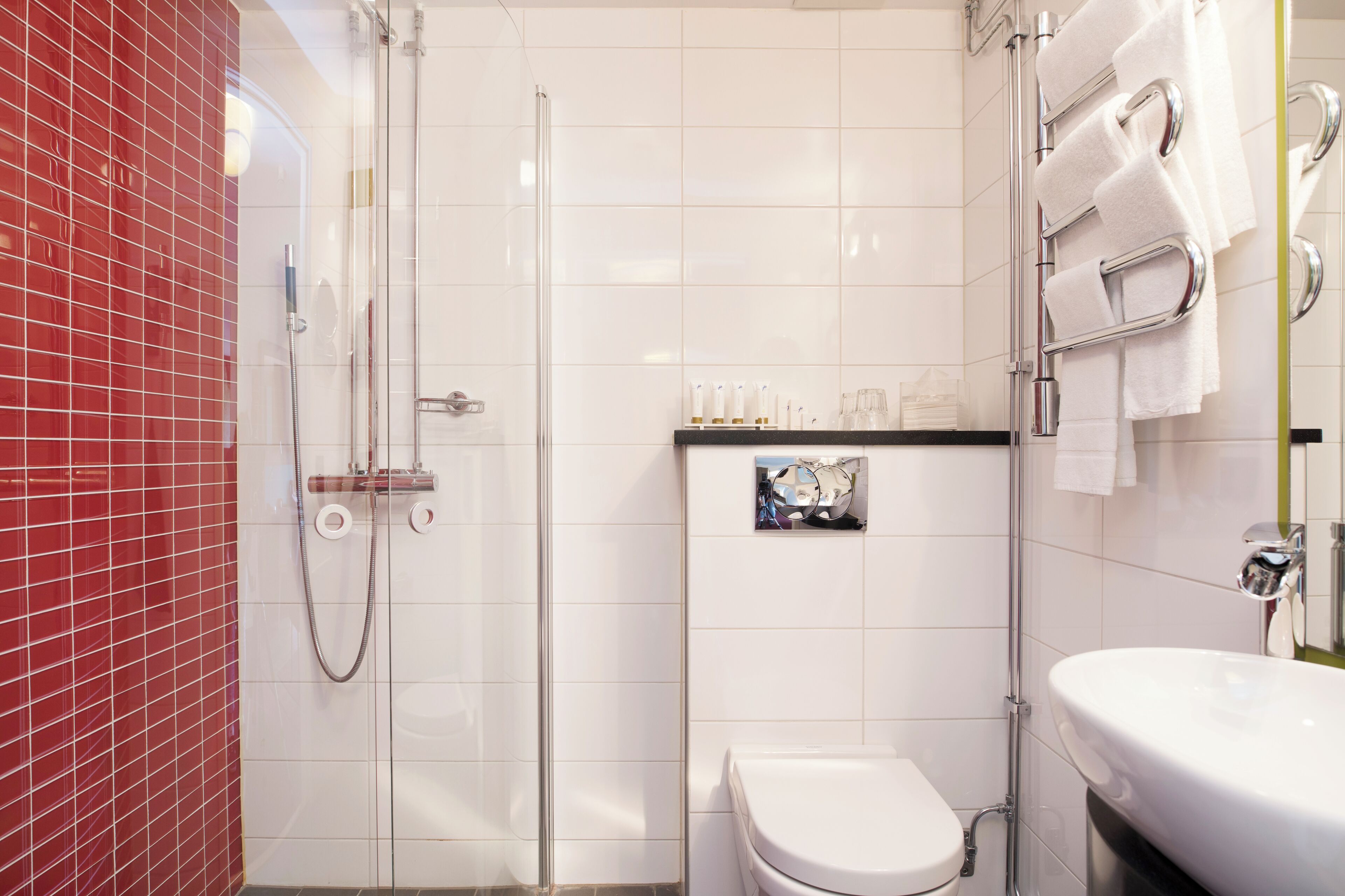 A modern bathroom with a glass-enclosed shower, a white toilet, and a sink with a towel rack.