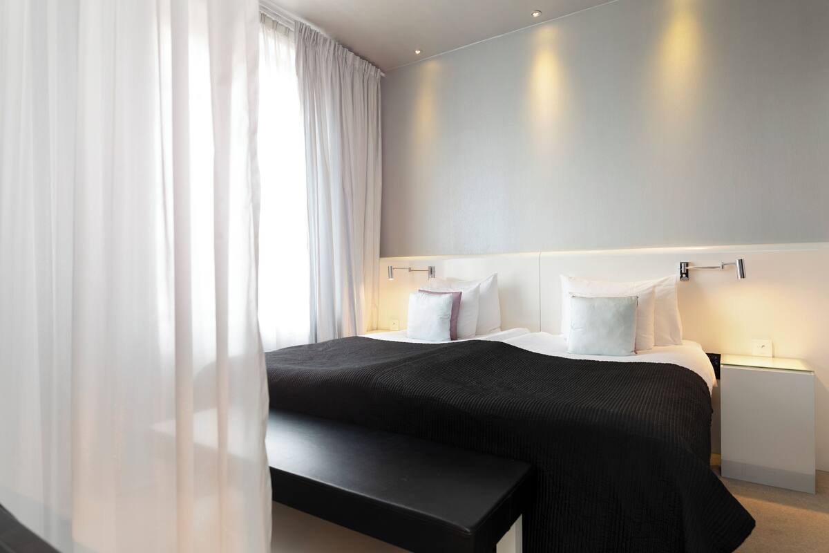 Ett modernt hotellrum med en stor säng, sängbord och en bänk.